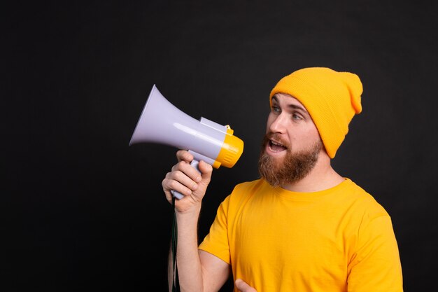 Attention! Homme européen criant dans un mégaphone sur fond noir