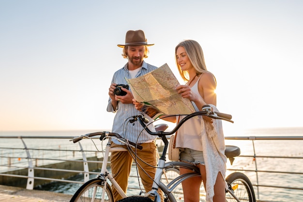 Attractive couple heureux voyageant en été sur des vélos, homme et femme aux cheveux blonds mode style hipster boho s'amuser ensemble