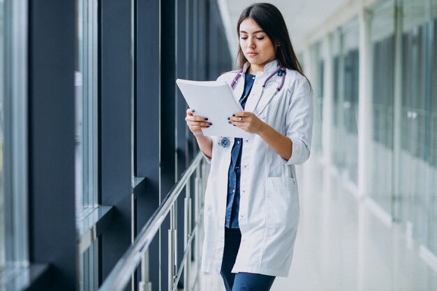 Attractive femme médecin debout avec des documents à l'hôpital