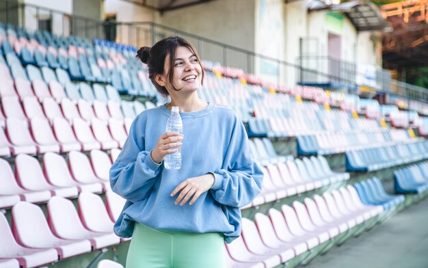 Attrayante jeune athlète féminine boit de l'eau après une séance d'entraînement