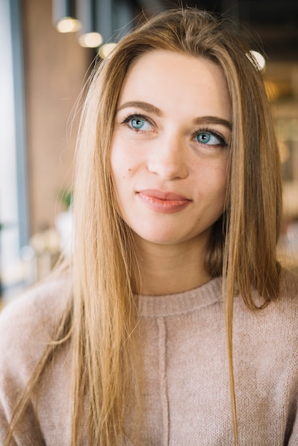 Attrayante positive jeune femme pensive au café