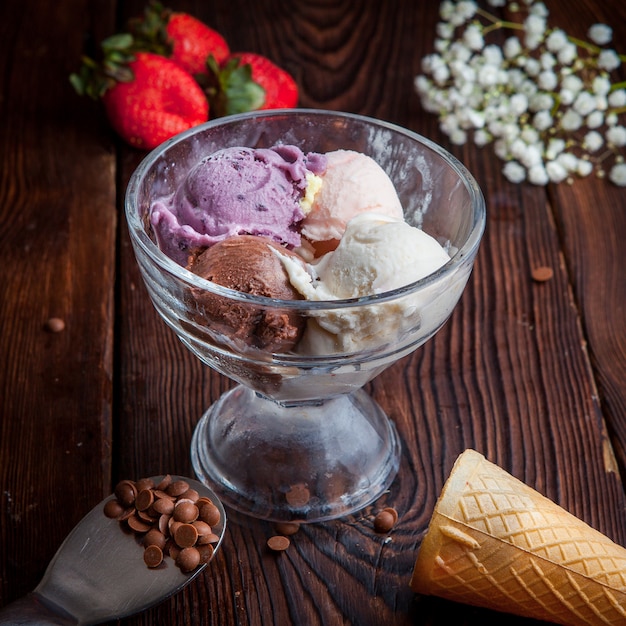 Au-dessus de boules de crème glacée avec des gouttes de fraise et de chocolat et de gypsophile et des cônes de gaufre dans une tasse de crème glacée