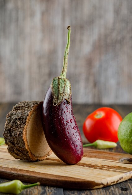 Aubergine au citron, tomate, poivrons, vue côté bois sur planche de bois et planche à découper