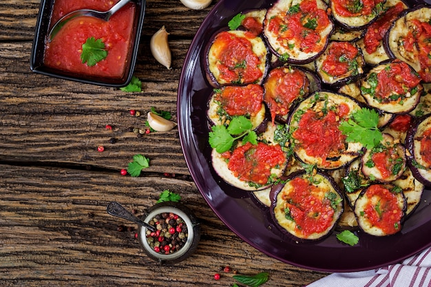 Aubergine grillée avec sauce tomate, ail, coriandre et menthe. Nourriture végétalienne. Aubergine grillée. Vue de dessus. Mise à plat