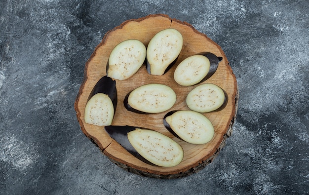 Aubergines crues en tranches sur planche de bois.