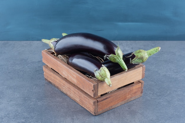 Aubergines fraîches mûres dans une boîte en bois.