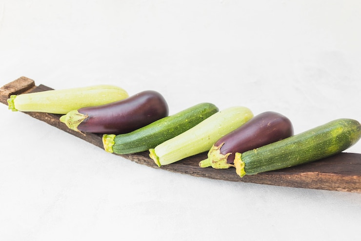 Photo gratuit aubergines récoltées entières colorées sur un plateau en bois sur fond blanc