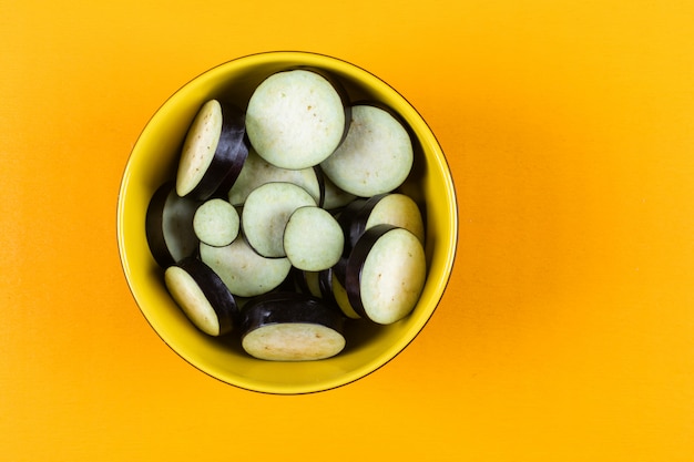 Aubergines en tranches dans un bol sur un jaune. vue de dessus.