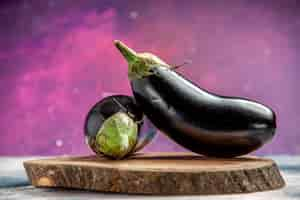 Photo gratuite aubergines vue de face sur planche de bois d'arbre sur rose