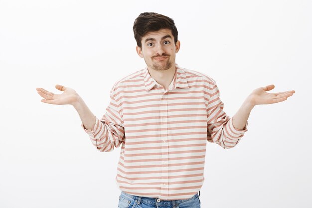 Aucune idée. Mannequin homme caucasien indifférent désemparé avec moustache, paumes étalées et haussant les épaules, ignorant et confus, souriant maladroitement