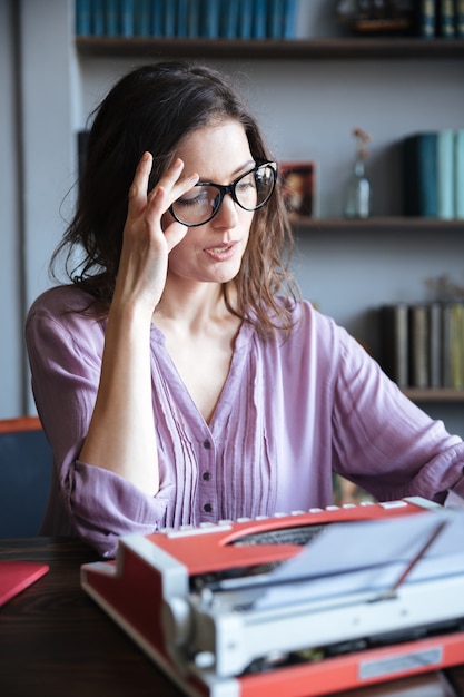 Auteure mûre pensive dans les lunettes en pensant et en regardant ailleurs