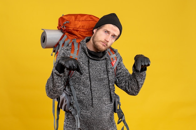 auto-stoppeur mâle bouleversé avec des gants en cuir et un sac à dos pointant vers le sol