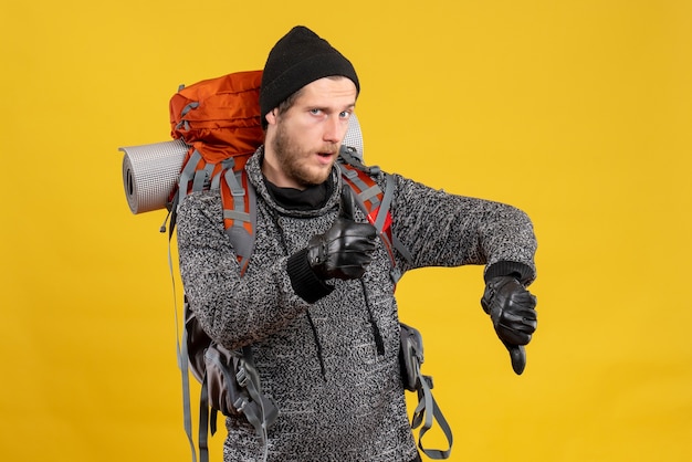 auto-stoppeur masculin avec des gants en cuir et un sac à dos donnant le signe du pouce vers le haut et vers le bas