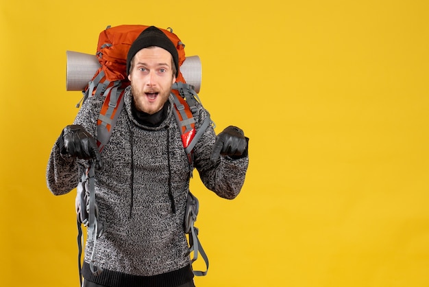 auto-stoppeur masculin avec des gants en cuir et un sac à dos pointant vers le sol