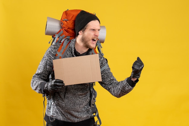 auto-stoppeur masculin se réjouit avec des gants en cuir et un sac à dos tenant un carton vierge exprimant ses sentiments