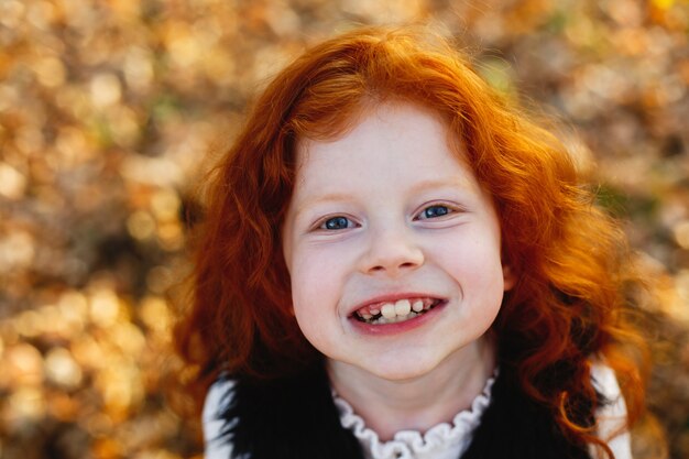 Automne automne, portrait d&#39;enfant. Charmante et rousse petite fille a l&#39;air heureux debout sur le l tombé