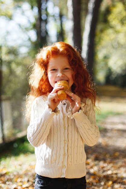 Automne automne, portrait d&#39;enfant. Charmante et rousse petite fille a l&#39;air heureux en mangeant une glace dans un
