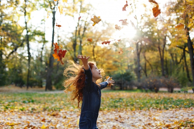 Automne automne, portrait d&#39;enfant. Charmante et rousse petite fille a l&#39;air heureux marchant et jouant sur t