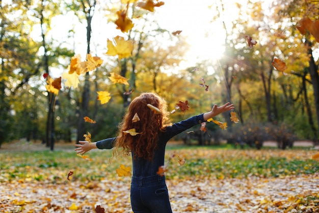 Photo gratuite automne automne, portrait d'enfant. charmante et rousse petite fille a l'air heureux marchant et jouant sur t