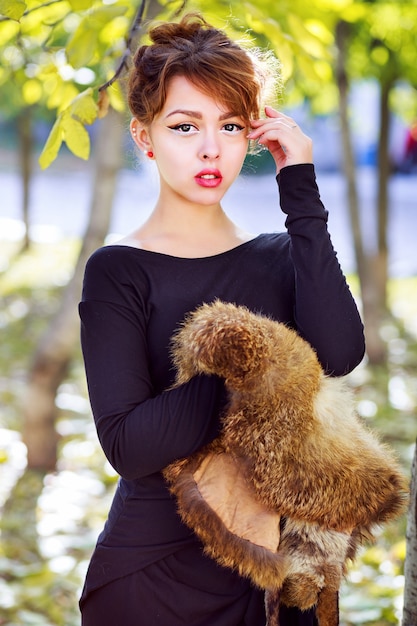 Photo gratuite automne mode portrait de mode de vie sexy belle femme asiatique portant de longues bottes élégantes maxi robe et tenant un morceau de fourrure, posant au parc de la ville dans une belle journée d'automne ensoleillée. couleurs vives.