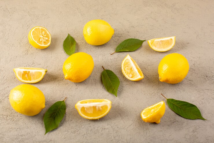 Photo gratuit un avant fermé vue jaune citrons frais mûrs moelleux et juteux entiers et tranchés avec des feuilles vertes bordées sur le gris
