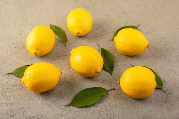 Un avant fermé vue jaune citrons frais mûrs moelleux juteux avec des feuilles vertes bordées sur le gris