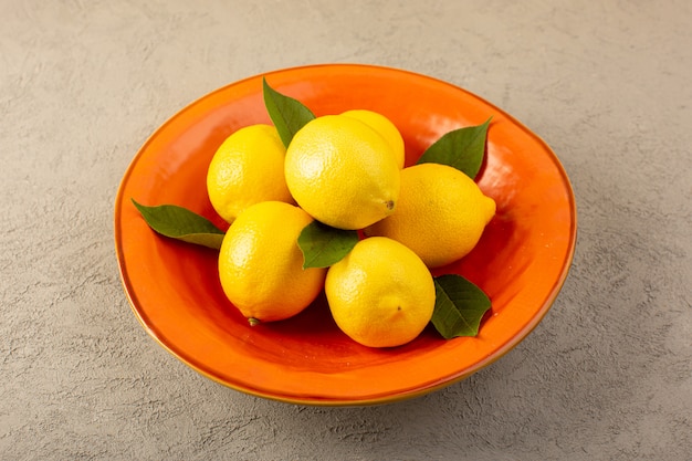 Un avant fermé vue jaune citrons frais mûrs moelleux juteux à l'intérieur de la plaque orange sur le gris