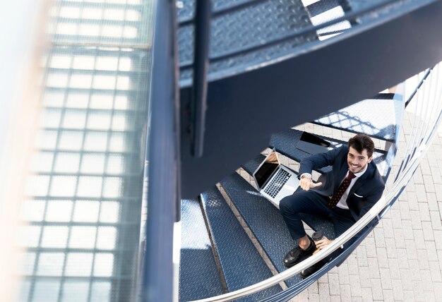 Avocat smiley à angle élevé assis dans les escaliers