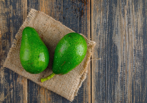 Avocats sur bois et morceau de sac. pose à plat.