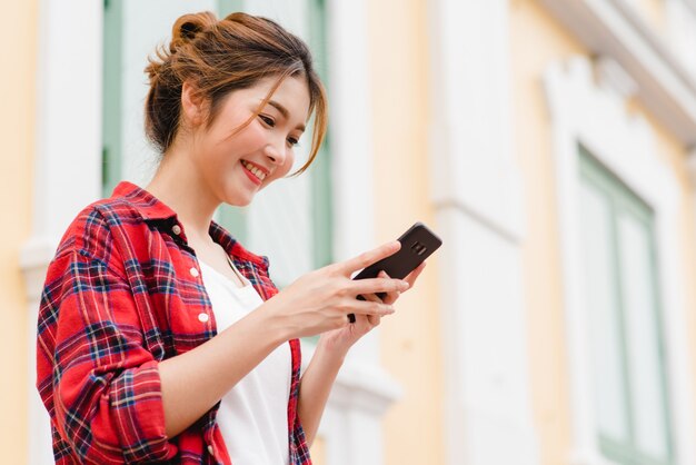 Backpacker de touristes asiatiques femme souriante et à l&#39;aide de smartphone voyageant seul