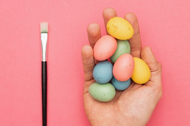 Badigeonner à côté de la main avec des œufs colorés