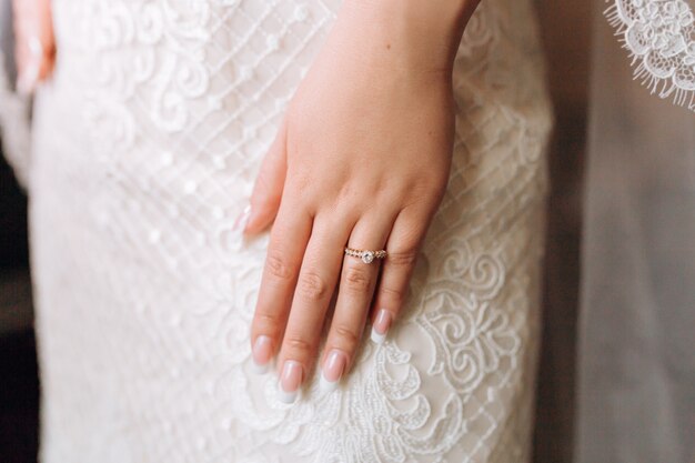 Bague de fiançailles sur la main de la mariée avec des pierres précieuses et une belle manucure française