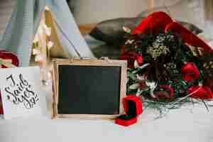 Photo gratuite bague et tableau noir près du bouquet et des cadeaux