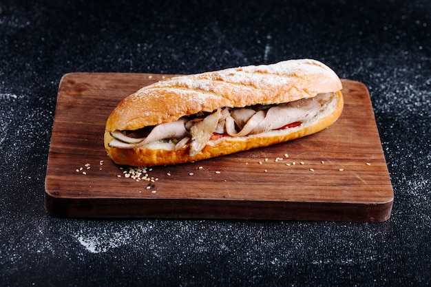 Baguette sandwich au jambon sur une planche de bois.