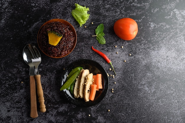 Baies de riz pourpre cuites avec du blanc de poulet grillé. Citrouille, carottes et feuilles de menthe dans un plat, aliments propres.