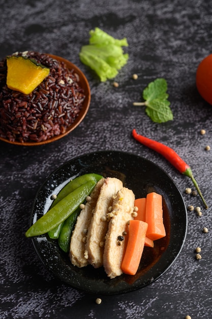 Baies de riz pourpre cuites avec du blanc de poulet grillé. Citrouille, carottes et feuilles de menthe dans un plat, aliments propres.