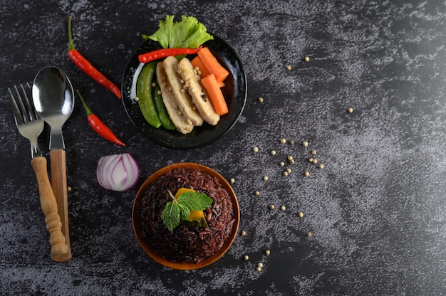 Baies de riz pourpre cuites avec du blanc de poulet grillé. Citrouille, carottes et feuilles de menthe dans un plat, aliments propres.