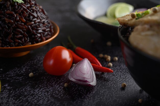 Baies de riz violet dans un bol avec oignons rouges, piment et tomates