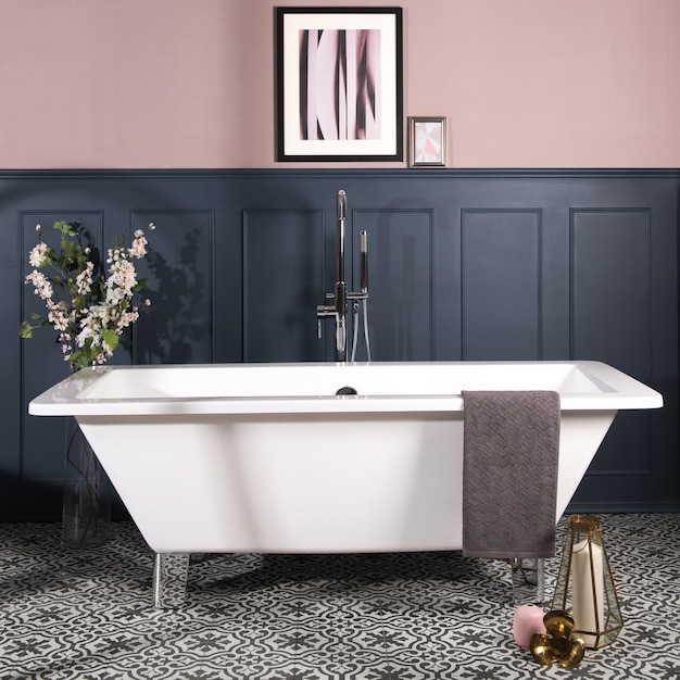 Baignoire dans une salle de bain avec des murs bleu foncé et rose pastel et un sol en carreaux de céramique à motifs