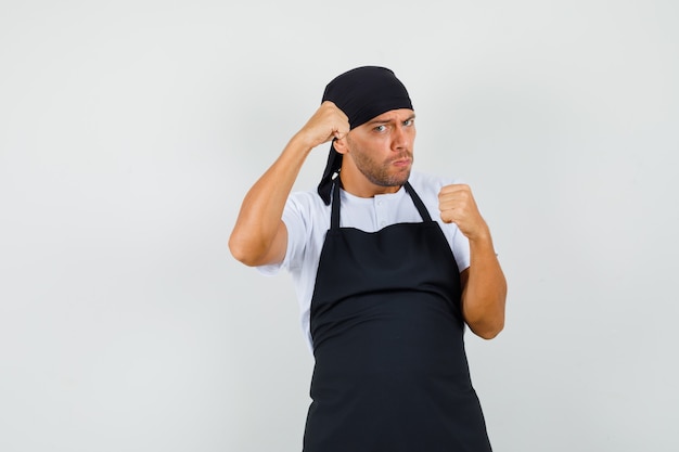 Baker homme debout en boxer pose en t-shirt, tablier et à forte