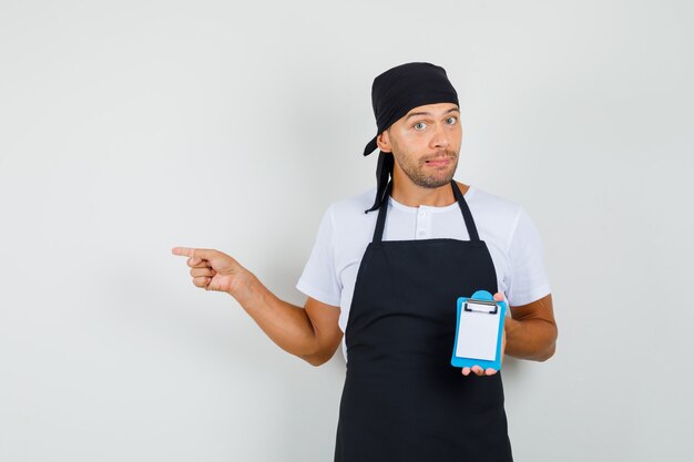 Baker man holding mini presse-papiers, pointant de côté en t-shirt