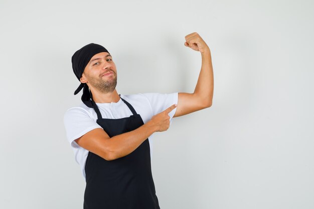 Baker man montrant ses muscles en t-shirt, tablier et à la confiance