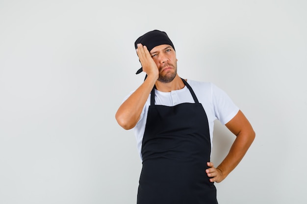 Baker man en t-shirt, tablier et à la pensive