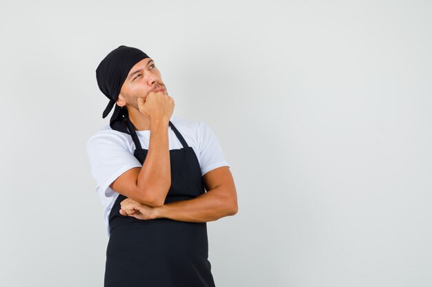 Baker man en t-shirt, tablier et à la pensive