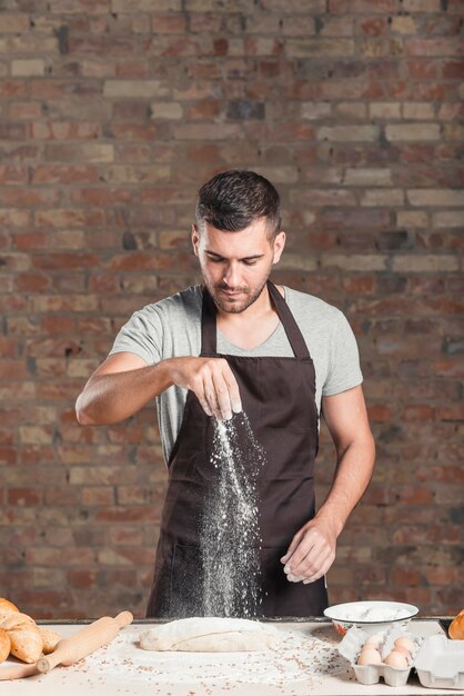 Baker saupoudrer de la farine sur la pâte préparée