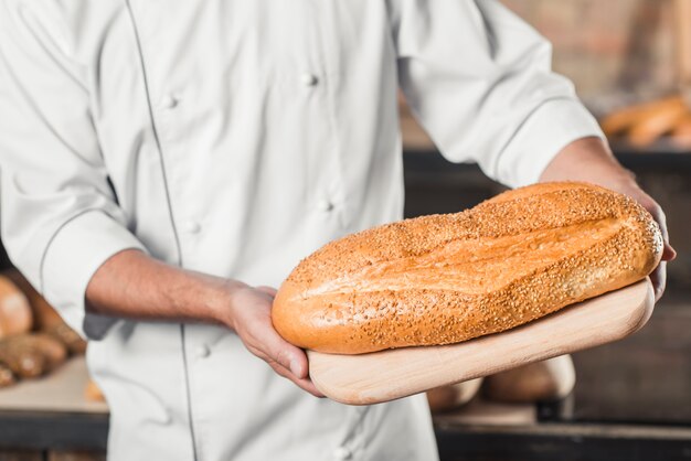 Baker tenant du pain frais sur une planche à découper