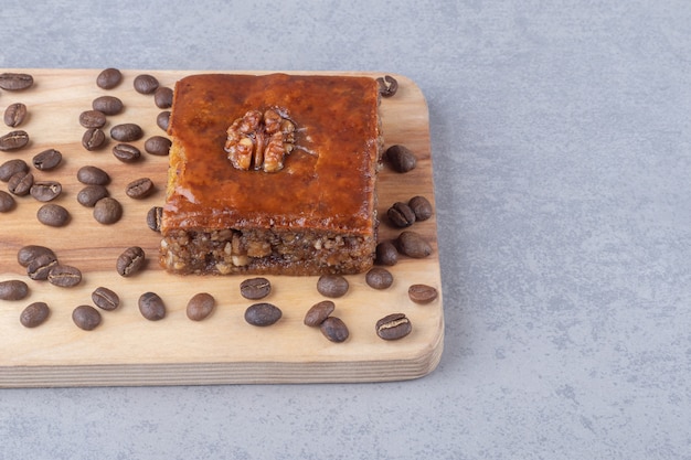 Bakhlava et grains de café sur une planche de bois sur une table en marbre.