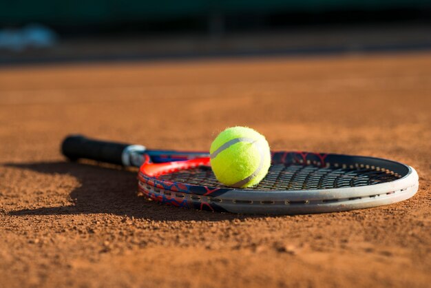balle de tennis gros plan sur une raquette posée sur le sol