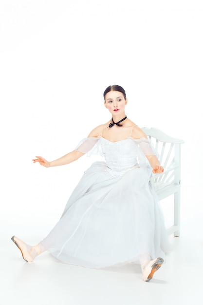 Ballerine en robe blanche assise, espace studio.