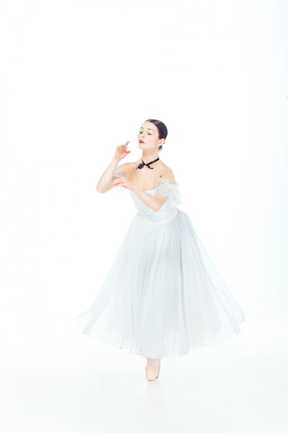 Ballerine en robe blanche posant sur des pointes, studio.